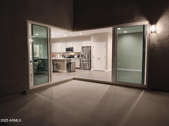 kitchen with stainless steel appliances, recessed lighting, light countertops, a textured wall, and white cabinets