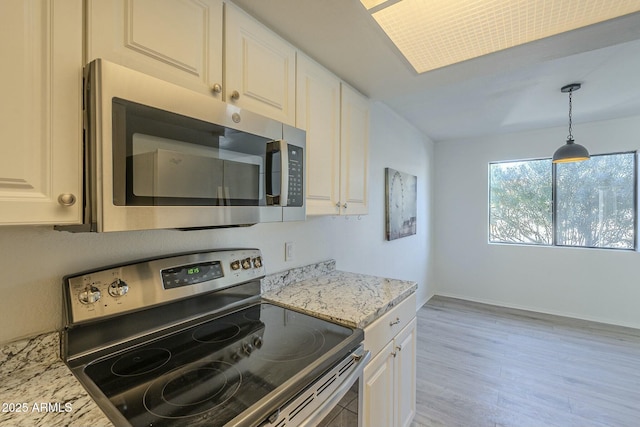 kitchen with decorative light fixtures, white cabinets, stainless steel appliances, light stone countertops, and light hardwood / wood-style flooring