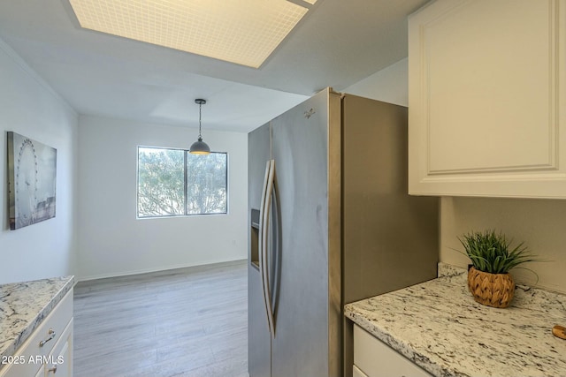 kitchen with stainless steel refrigerator with ice dispenser, white cabinetry, light stone counters, pendant lighting, and light hardwood / wood-style floors