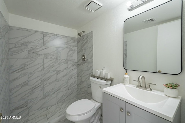 bathroom featuring tiled shower, vanity, and toilet