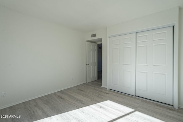 unfurnished bedroom with light hardwood / wood-style flooring and a closet