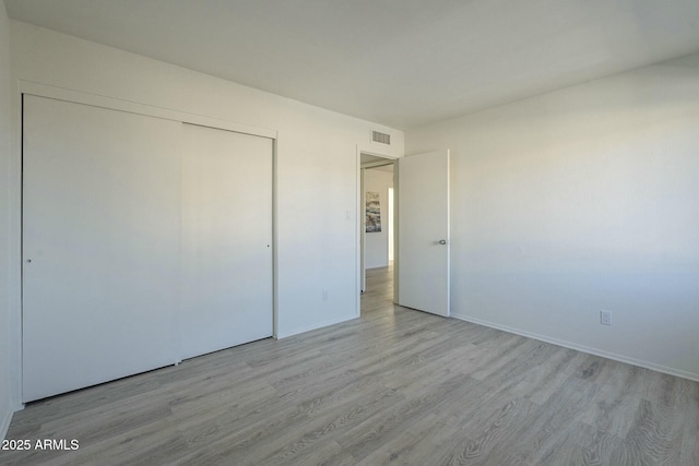 unfurnished bedroom featuring light hardwood / wood-style floors and a closet