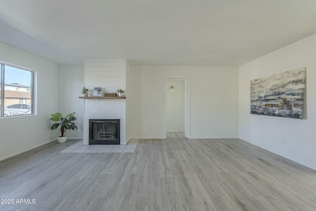 unfurnished living room featuring crown molding, a fireplace, and light hardwood / wood-style flooring