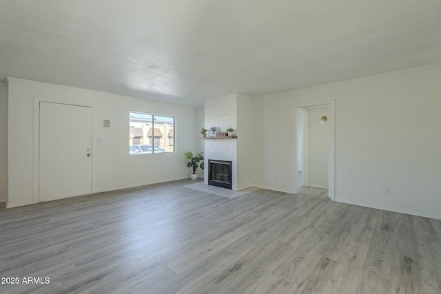 unfurnished living room featuring a brick fireplace and light hardwood / wood-style floors