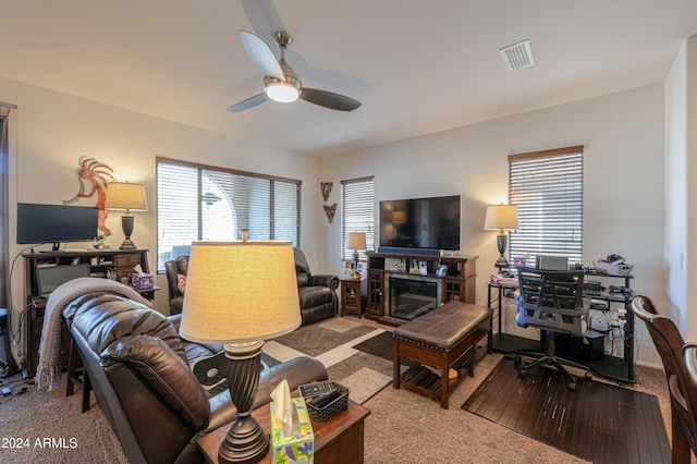 carpeted living room with ceiling fan and a fireplace