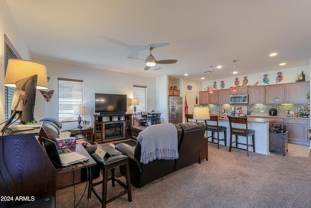 carpeted living room featuring a fireplace and ceiling fan