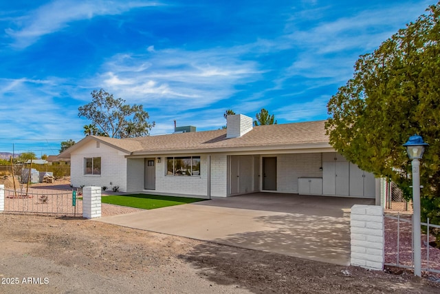 single story home featuring driveway, brick siding, roof with shingles, and fence