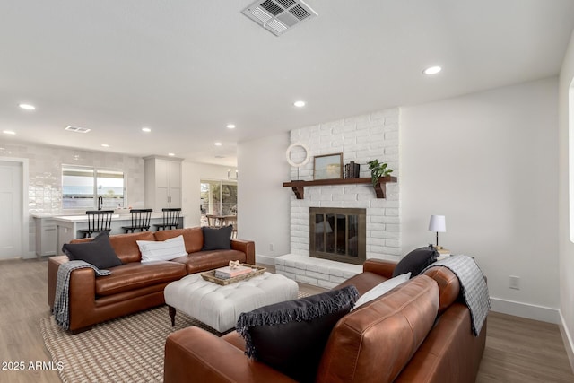 living area featuring recessed lighting, visible vents, a fireplace, and light wood-style flooring