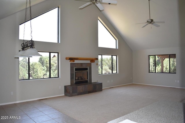 unfurnished living room featuring high vaulted ceiling, a tile fireplace, carpet flooring, a ceiling fan, and baseboards