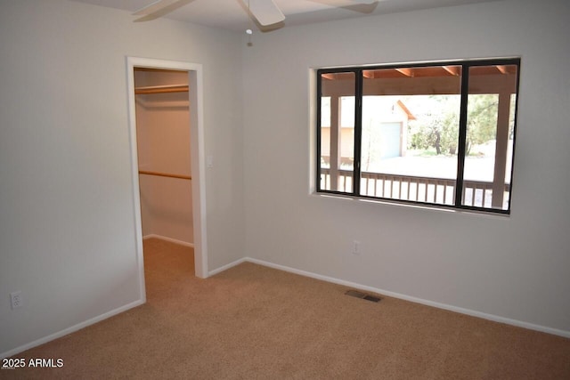 unfurnished bedroom with a walk in closet, baseboards, carpet floors, visible vents, and a closet