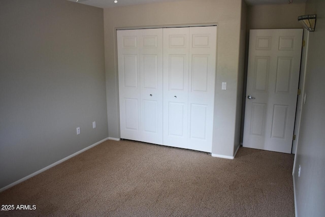 unfurnished bedroom with baseboards, a closet, and carpet flooring