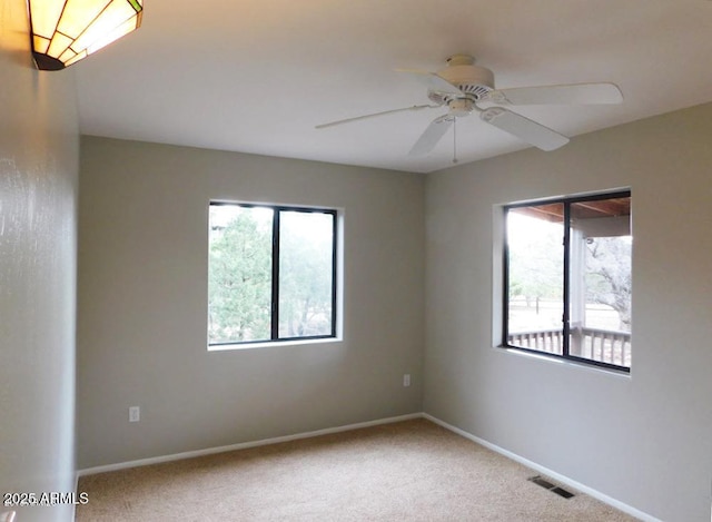 spare room featuring plenty of natural light, carpet, baseboards, and visible vents