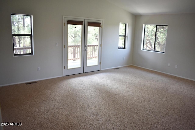 unfurnished room featuring lofted ceiling, visible vents, french doors, and light colored carpet