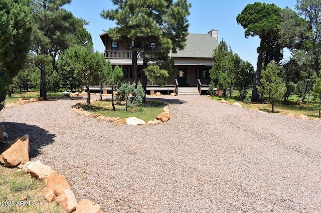 view of front of house with driveway, covered porch, and a chimney