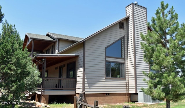view of side of home with a chimney, a shingled roof, and a porch