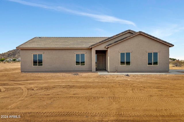 ranch-style home featuring a tile roof and stucco siding