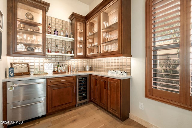 bar with light hardwood / wood-style floors, light stone countertops, tasteful backsplash, and beverage cooler