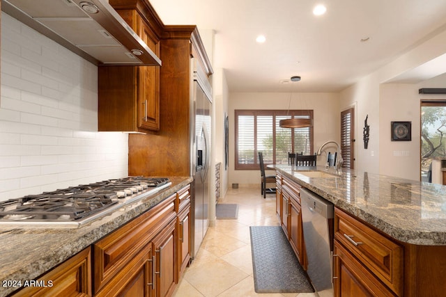 kitchen featuring appliances with stainless steel finishes, a healthy amount of sunlight, tasteful backsplash, and wall chimney range hood