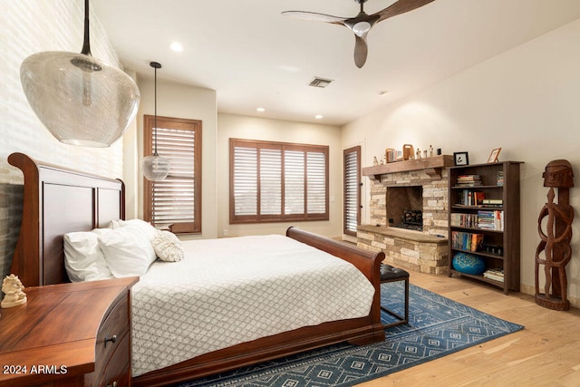 bedroom with ceiling fan, light hardwood / wood-style flooring, and a fireplace