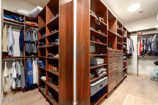 walk in closet with light hardwood / wood-style floors