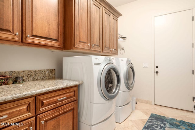 clothes washing area with light tile patterned flooring, cabinets, and washer and clothes dryer