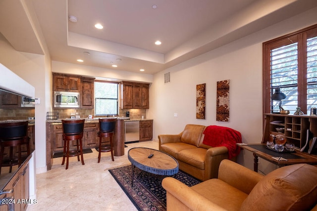 living room featuring a raised ceiling and plenty of natural light