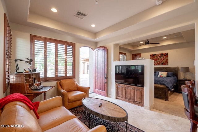 carpeted living room featuring a tray ceiling and ceiling fan