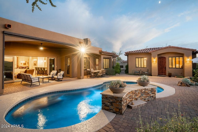 pool at dusk featuring a patio area and an outdoor living space