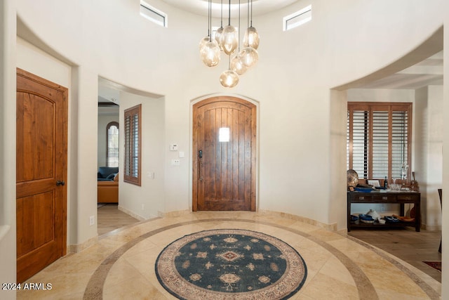 entrance foyer with light hardwood / wood-style floors, a notable chandelier, and a towering ceiling