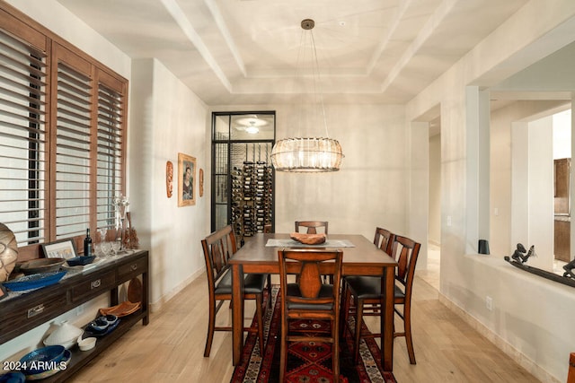 dining area featuring a raised ceiling, an inviting chandelier, and light wood-type flooring