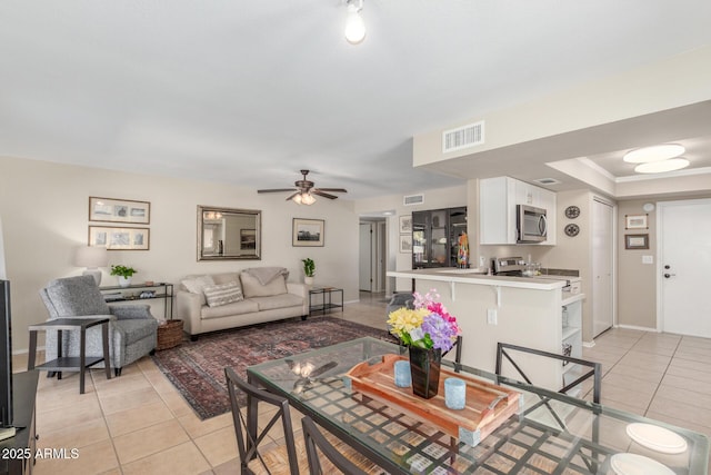 living area featuring light tile patterned floors, baseboards, visible vents, and ceiling fan