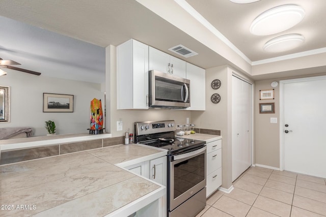 kitchen featuring visible vents, crown molding, light tile patterned floors, appliances with stainless steel finishes, and white cabinets