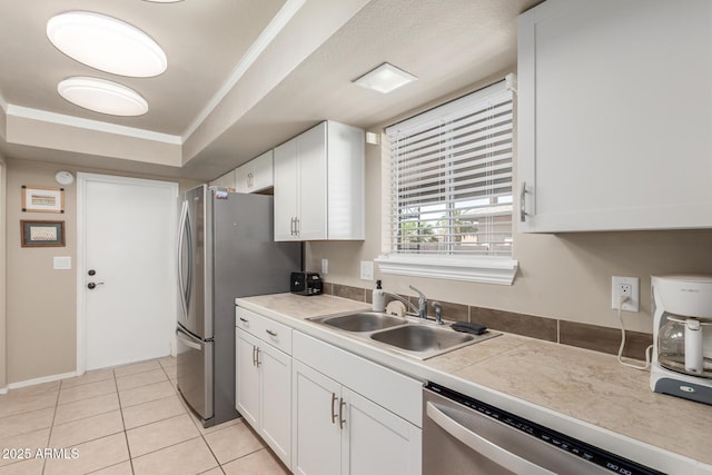 kitchen with ornamental molding, light tile patterned floors, white cabinets, stainless steel appliances, and a sink