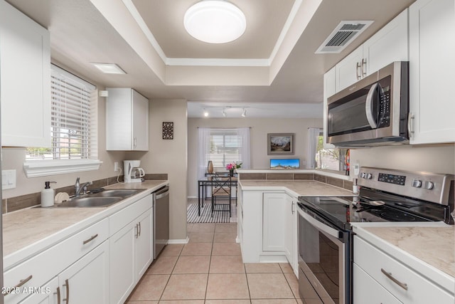 kitchen featuring visible vents, a tray ceiling, light tile patterned flooring, white cabinets, and appliances with stainless steel finishes