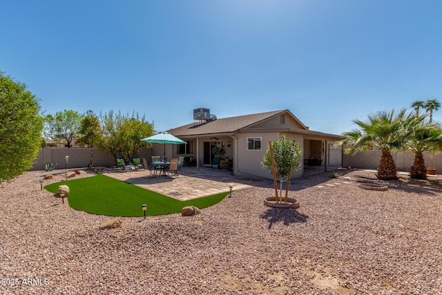 rear view of property featuring a fenced backyard and a patio area