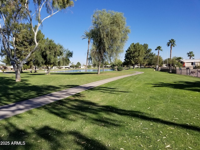 view of community with a yard, a water view, and fence