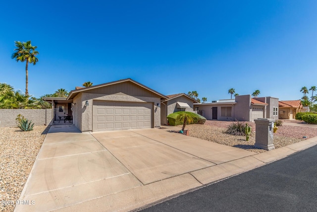 view of front facade with a gate, fence, driveway, an attached garage, and stucco siding