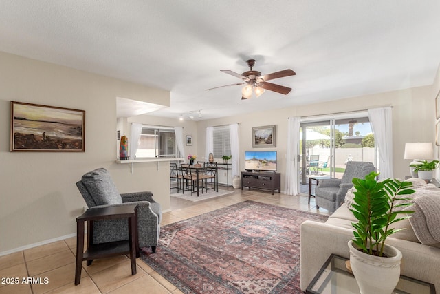 living room with light tile patterned floors, baseboards, and ceiling fan