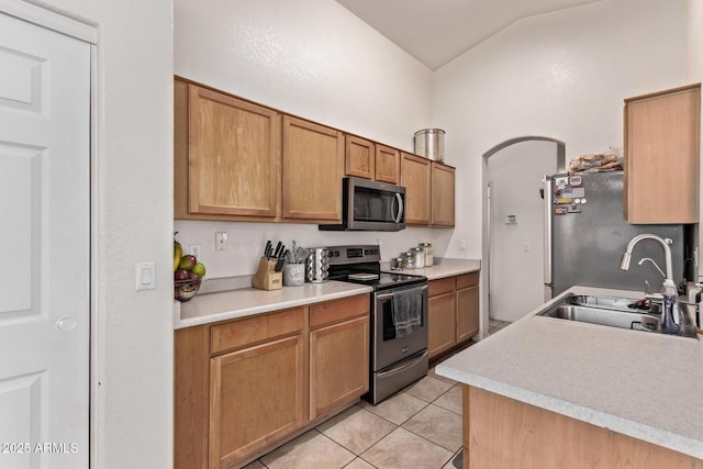 kitchen with lofted ceiling, sink, light tile patterned floors, and stainless steel appliances