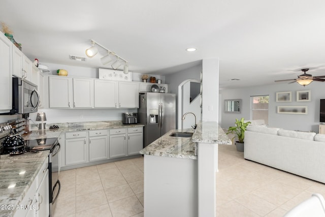 864 S 223rd Ln, Buckeye, AZ 85326 - kitchen featuring stainless steel appliances, a sink, open floor plan, light stone countertops, and a ceiling fan