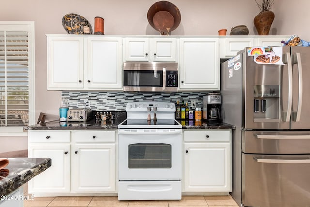 kitchen featuring dark stone countertops, white cabinets, appliances with stainless steel finishes, and light tile patterned floors