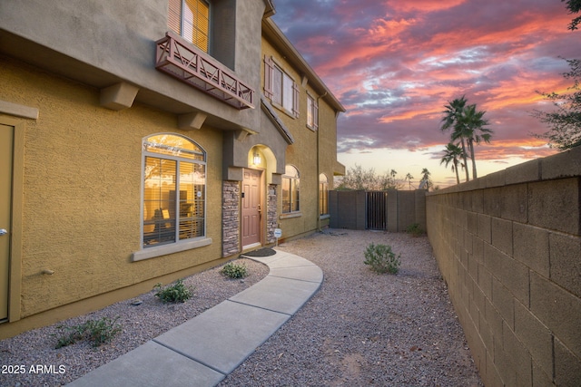 17150 N 23rd St Unit 125, Phoenix, AZ 85022 - exterior entry at dusk featuring a gate, stucco siding, and a balcony