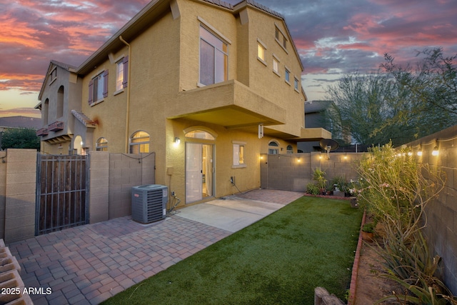 17150 N 23rd St Unit 125, Phoenix, AZ 85022 - back of property at dusk featuring central AC, stucco siding, and a patio