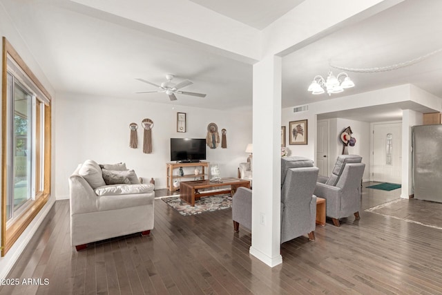 living room with dark hardwood / wood-style flooring and ceiling fan with notable chandelier