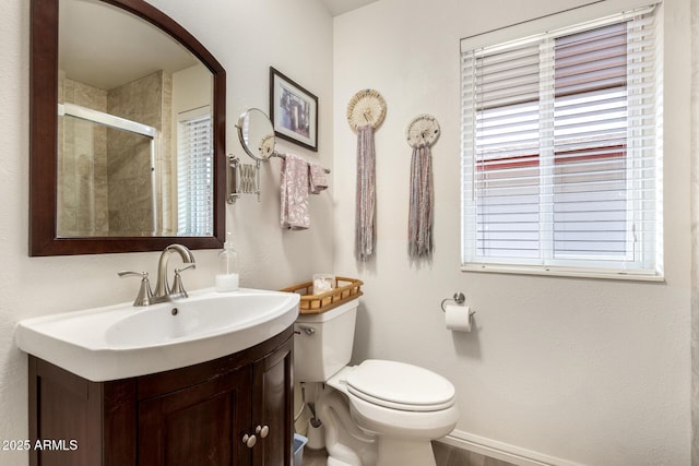 bathroom featuring a healthy amount of sunlight, toilet, a shower with door, and vanity