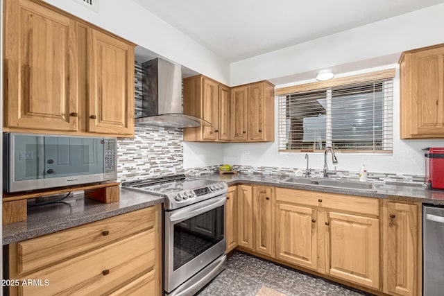 kitchen featuring appliances with stainless steel finishes, sink, backsplash, dark stone counters, and wall chimney range hood