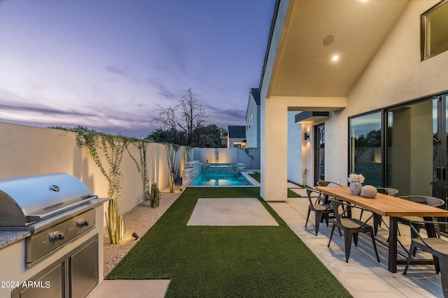 patio terrace at dusk featuring a yard, a fenced in pool, and area for grilling