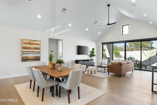 dining space with ceiling fan, light hardwood / wood-style flooring, and high vaulted ceiling