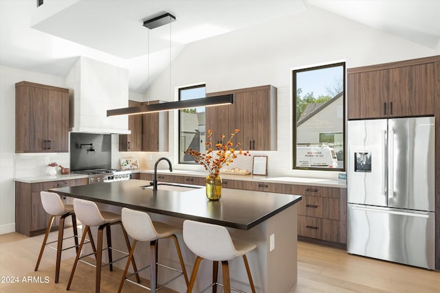 kitchen with a kitchen island with sink, sink, lofted ceiling, and appliances with stainless steel finishes