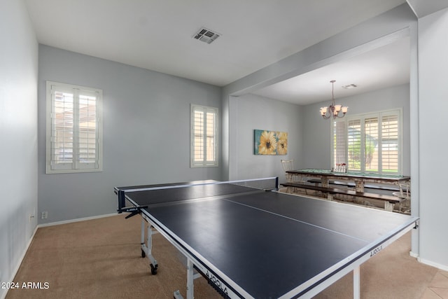 recreation room with a chandelier, light carpet, and plenty of natural light